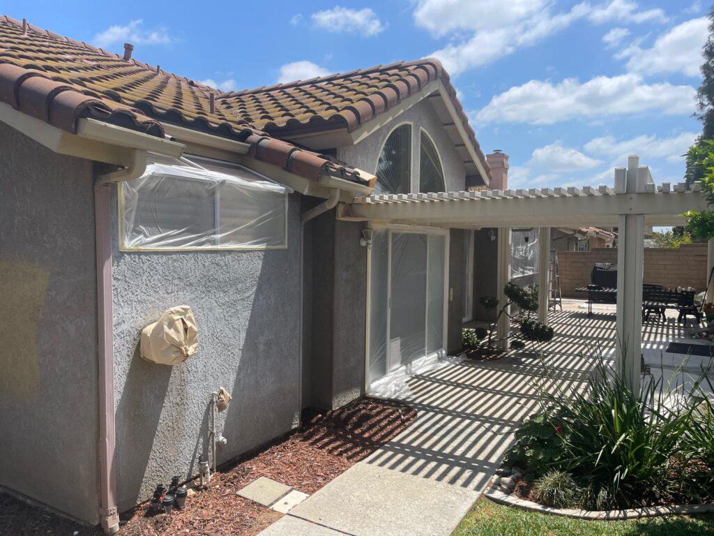 Exterior house painting with protective plastic coverings and fresh paint. Skilled residential paint.