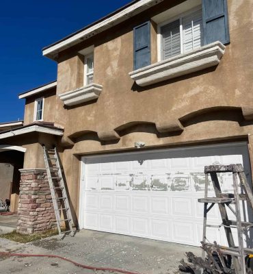 Exterior house painting with fresh beige and blue accents, showcasing professional painting services.
